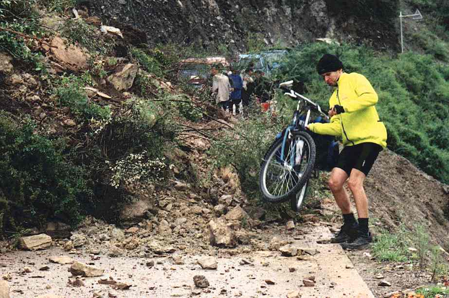 Mark carrying his bike over the landslide